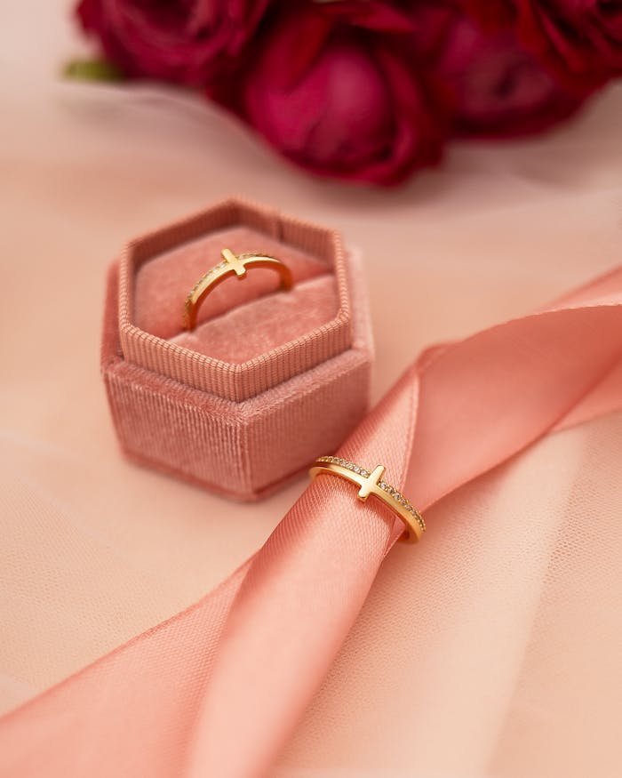 A close-up of a gold ring in a velvet box with roses in the background, perfect for jewelry ads.